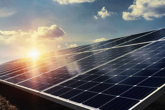 Erneuerbare Energien im Unternehmen - Solarmodule vor einem leuchtenden Himmel bei Sonnenuntergang, die die Nutzung erneuerbarer Energien symbolisieren.